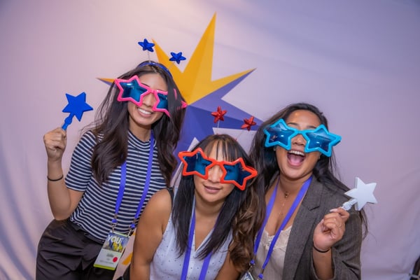 Fun at pharma event- 3 women pose in star sunglasses at photobooth