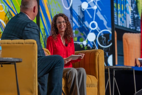 Man and woman talk on stage at pharma event