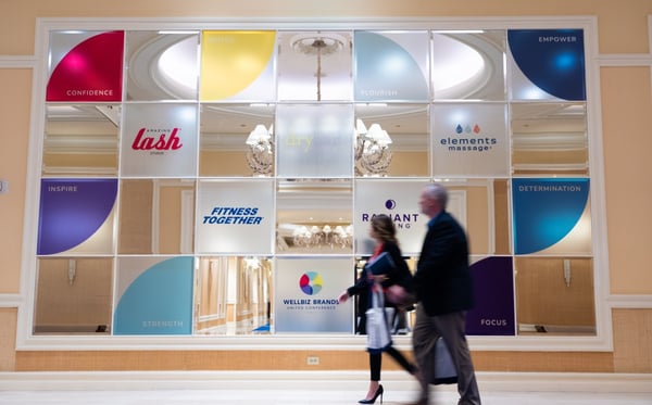 attendees walk past branded wall