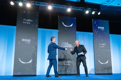 Speakers fist bump on conference stage