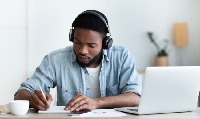 young Black man takes notes during virtual event 293567722