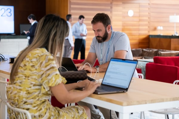 a man and woman sit at table where event attendees provide event feedback online 