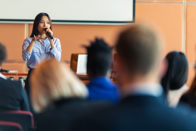 Asian woman talks to audience at a conference1034036368