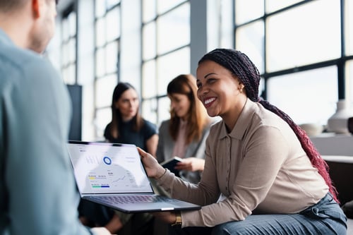 Smiling woman presenting analytics on laptop