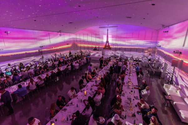 attendees at dinner with the Eiffel Tower projected on the walls