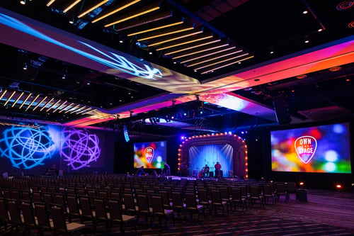 Event ballroom setup with dynamic lighting and screens on stage