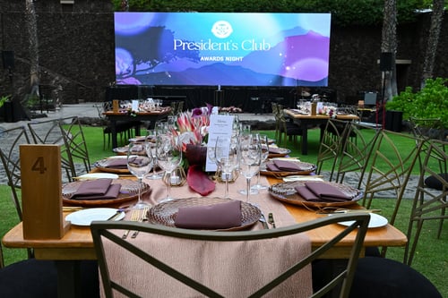Formally set table at incentive program with a screen that says President's Club
