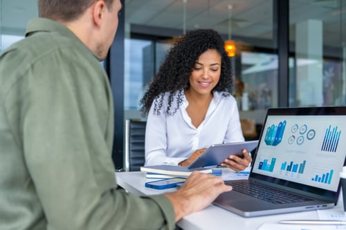Young man and woman working on a lap top and tablet smiling
