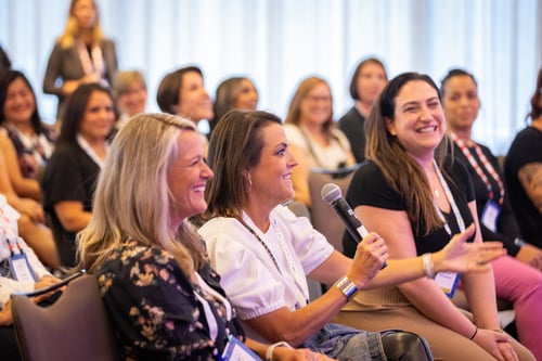 Audience member holding a microphone asking a question during a conference session