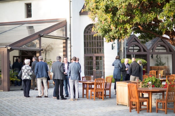 attendees at pharma event stand in courtyard with tables and talk in groups