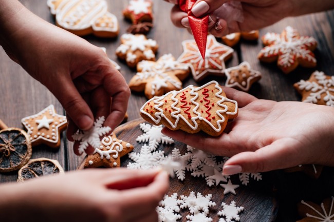 two sets of hands decorating christmas cookies295585621