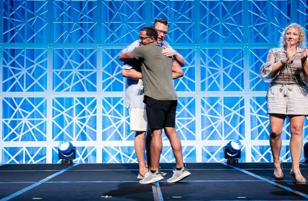 employee recognition event two men hug on stage