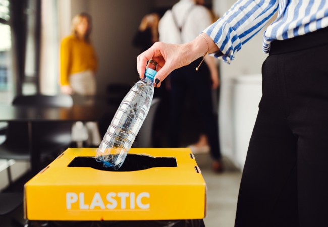 woman places plastic bottle in recycling bin