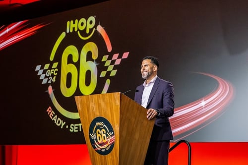 Smiling man standing behind podium on a stage