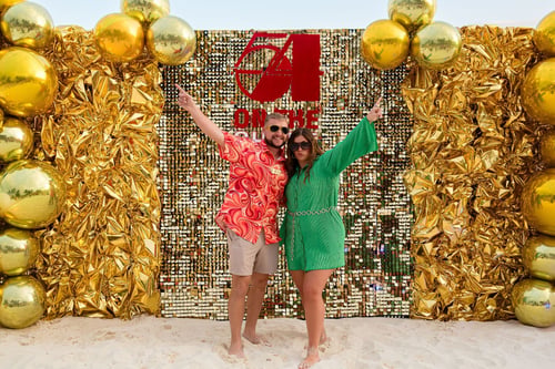 Man and woman posing on the beach with gold balls