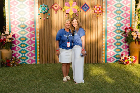 Two women posing in front of a colorful backdrop